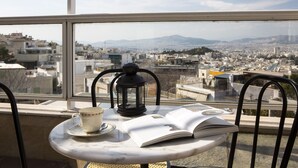 Ein Tisch mit Tasse, Laterne und offenem Buch, mit Blick auf eine Stadtlandschaft durch ein Fenster.