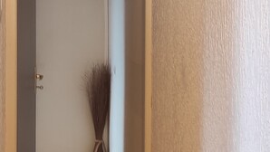 Ein Korridor mit Holzboden, einer weißen Wand mit Struktur und einer Tür zu einem weiteren Raum.