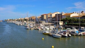 Eine Marina mit zahlreichen Schiffen, die an einer Uferpromenade liegen, umgeben von Gebäuden unterschiedlicher Architektur.