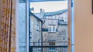 A room with a large window, a door, and a small stuffed toy on the floor. - Gorgeous Grassmarket Apartment! In quiet & secure courtyard in central Old Town (Edinburgh)