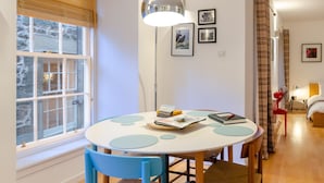 A dining area with a round table, blue chairs, and a floor lamp. - Gorgeous Grassmarket Apartment! In quiet & secure courtyard in central Old Town (Edinburgh)