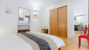 A bedroom with a bed, a wooden wardrobe, a chair, a small table, and a fan. - Gorgeous Grassmarket Apartment! In quiet & secure courtyard in central Old Town (Edinburgh)