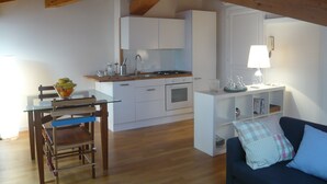 Een knus woongedeelte met een keuken, eethoek en een bank.