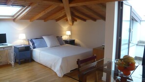 Een slaapkamer met een bed, nachtkastjes, een bureau en een glazen tafel met fruit.