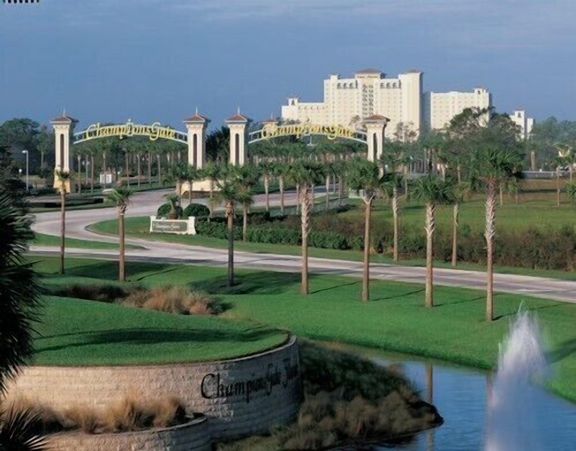 A golf course with a fountain, palm trees, and a large hotel in the background.