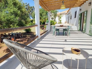 Un patio techado al aire libre con una mesa, sillas, una lámpara colgante y un cerco de madera.
