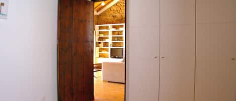 Ein Zimmer mit einer Holztür, einem weißen Kleiderschrank und einer Steinwand im Hintergrund.