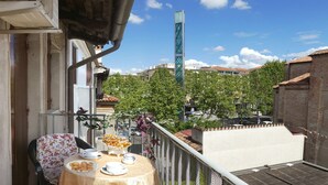 A balcony with a table set for two, a chair, and a decorative bowl with flowers.