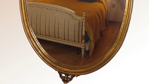 A bedroom with a bed, two bedside lamps, a wall clock, and a ceiling light fixture.