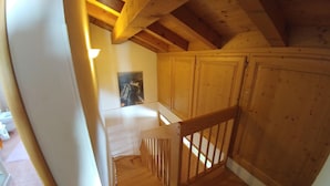A wooden staircase with a white railing leading to a room with wooden walls and a ceiling with exposed beams. - APARTMENT IN THE WHITE MAGIC OF THE DOLOMITES (Laggio di Cadore)