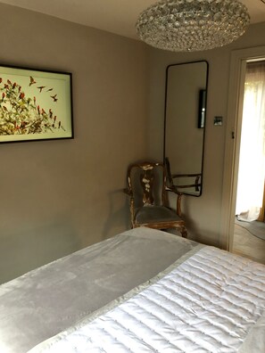 Relax in a serene space with a large bed, a comfortable chair, and a framed picture of birds.
