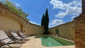 A courtyard with a swimming pool, lounge chairs, and stone walls. - Spacious house between Siena e Firenze with private swimming pool, A/C and Wi-Fi (Radicondoli)