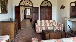 A room with a sofa, a wooden cabinet, a bench, a fireplace, and a hallway leading to another room. - Spacious house between Siena e Firenze with private swimming pool, A/C and Wi-Fi (Radicondoli)