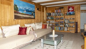 A cozy room with a sofa, a coffee table, and a bookshelf filled with books. - 2 BALCONIES,1 TERRACE,VIEWS OF  WATERFALL, MOUNTAINS, RIVER,WENGEN,TRAINS, (Lauterbrunnen)