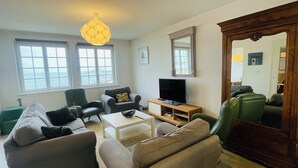 A living room with a sofa, armchairs, a coffee table, a TV, and a large mirror. - BZ sea view and close to town center (Roscoff)