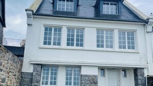 A two-story house with a white facade, multiple windows, and a stone wall on the left. - BZ sea view and close to town center (Roscoff)