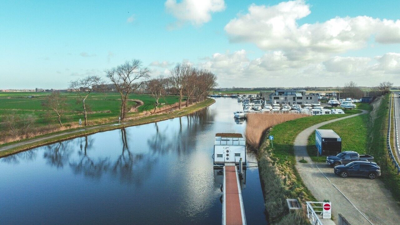 Un canal con barcos, un puente y un estacionamiento con automóviles.