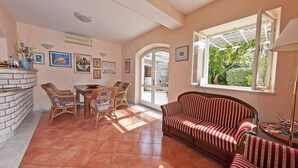 A spacious living room with a fireplace, a dining area, and a large window offering a view of the outdoors. - Gorgeous villa with unforgettable view and swimming pool (Dubrovnik)