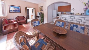 A spacious living area with a wooden dining table, wicker chairs, and a sofa. - Gorgeous villa with unforgettable view and swimming pool (Dubrovnik)