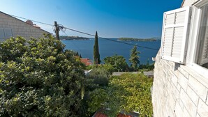 A view of a coastal area with a clear sky, a body of water, and a building with a sloped roof. - Gorgeous villa with unforgettable view and swimming pool (Dubrovnik)