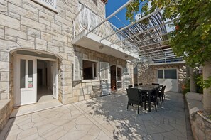 Edificio de piedra con un patio cubierto que tiene una mesa y sillas.
