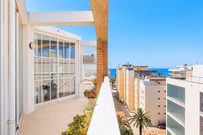 A modern building with large windows, a balcony with plants, and a view of the sea. - AirCon Penthouse Sea Views · Parking Pool · CENTER II 113 (Salou)