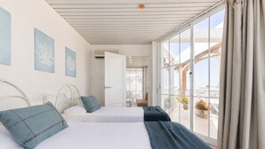 Een hotelkamer met twee bedden, een balkon met plantenbakken en uitzicht op de stad.
