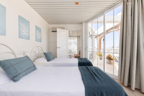 A hotel room with two beds, a balcony with potted plants, and a view of the city. - AirCon Penthouse Sea Views · Parking Pool · CENTER II 113 (Salou)