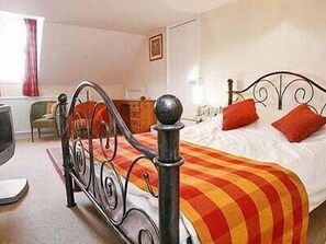 A bedroom with a metal bed frame, a red and yellow striped blanket, and a white bedspread. - Large Holiday Cottage for families, groups near Bude in Cornwall (Bude)