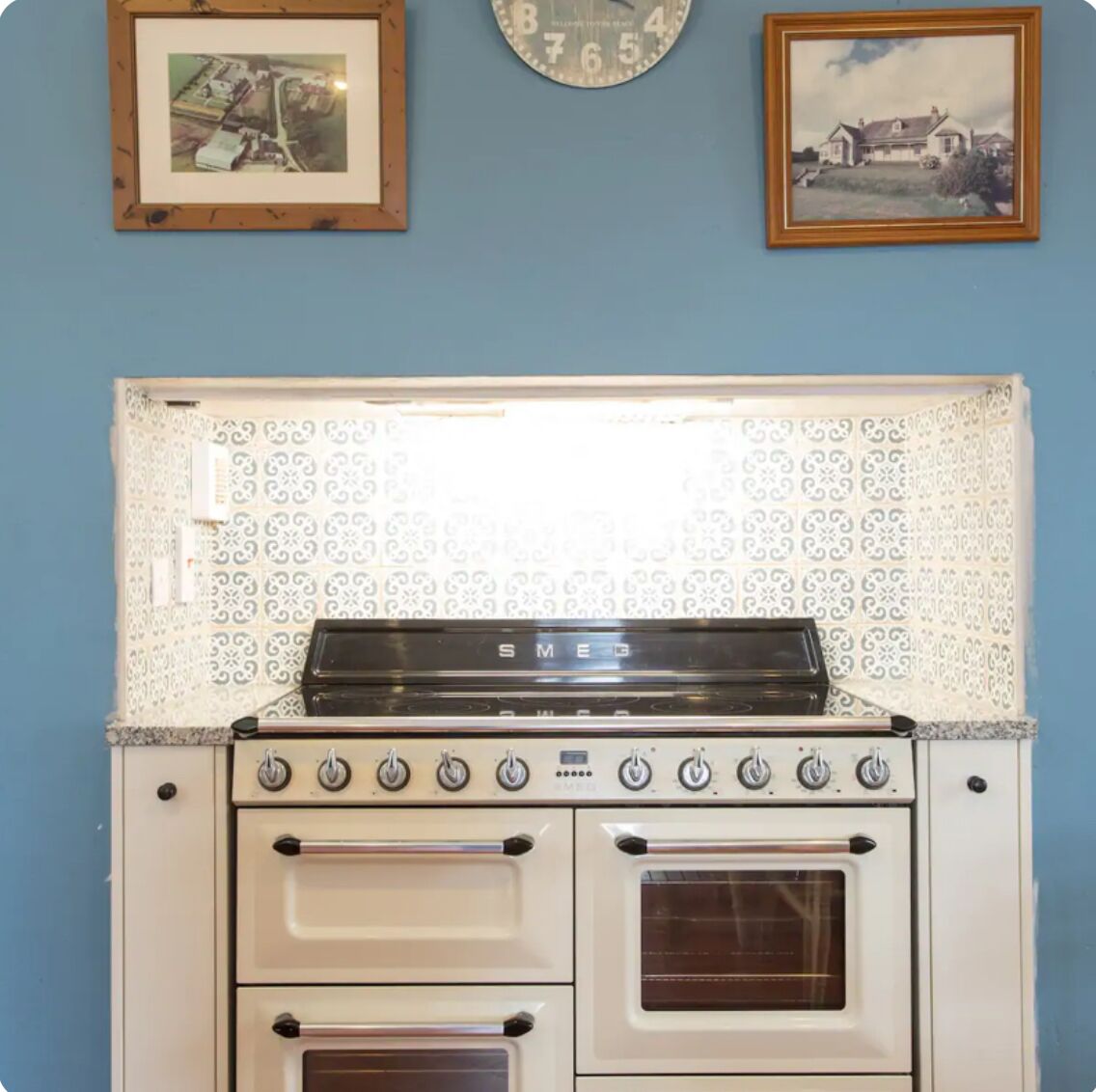 A kitchen with a white stove, two ovens, and a patterned backsplash.