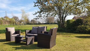 An outdoor seating area with wicker furniture and a grassy lawn. - Hinton Lodge - Quaint Victorian four star cottage in a quiet rural location. (Trowbridge)