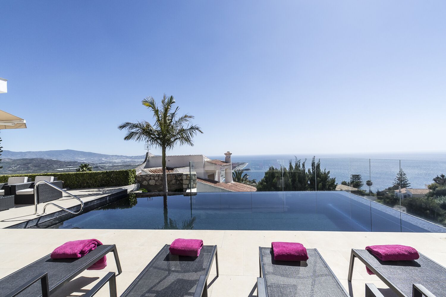 An infinity pool with lounge chairs and a view of the ocean.