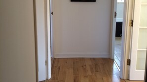 A hallway with wooden flooring, white walls, and a Buddha painting. - Beautiful Kingston apartment (Kingston upon Thames)