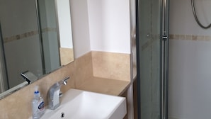 A bathroom with a white sink, a mirror, and a glass shower enclosure. - Beautiful Kingston apartment (Kingston upon Thames)