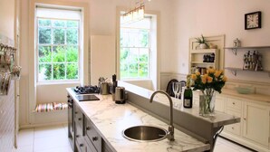 Una cocina moderna con encimera de mármol, pileta de acero inoxidable y ventanas amplias.