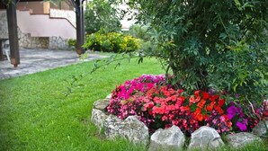 Un jardin avec un parterre de fleurs bordé de rochers et une pelouse.