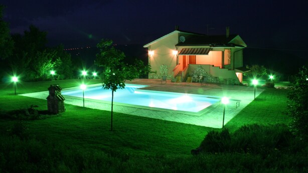 Une maison avec une piscine, entourée d’une pelouse bien entretenue et d’arbres.