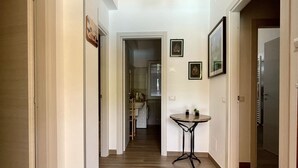 Un couloir doté d’un plancher en bois, une table sur laquelle est posée une petite plante, et des tableaux encadrés accrochés aux murs.