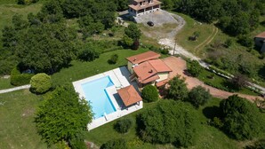Une grande maison avec une piscine et un bâtiment séparé doté d’un balcon.