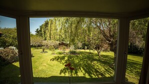 A view through a window of a well-maintained garden with a wooden structure in the background.