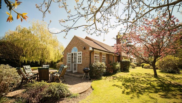 A brick house with a garden patio, outdoor seating, and a lawn.