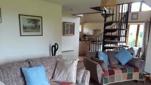 A living room with a sofa set, a staircase, and a dining area.