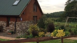 A rustic building with a green roof, stone wall, and wooden door.