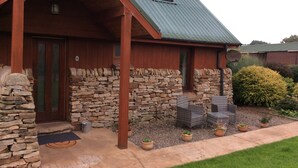 A rustic lodge with a stone exterior, a wooden porch, and a metal roof.