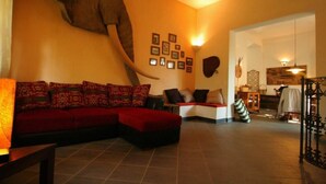 A living room with a large elephant head mural, a red sofa, and a patterned wall.