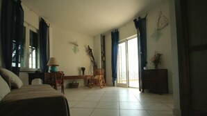 A bedroom with a bed, a desk, a chair, a dresser, and a window with curtains.