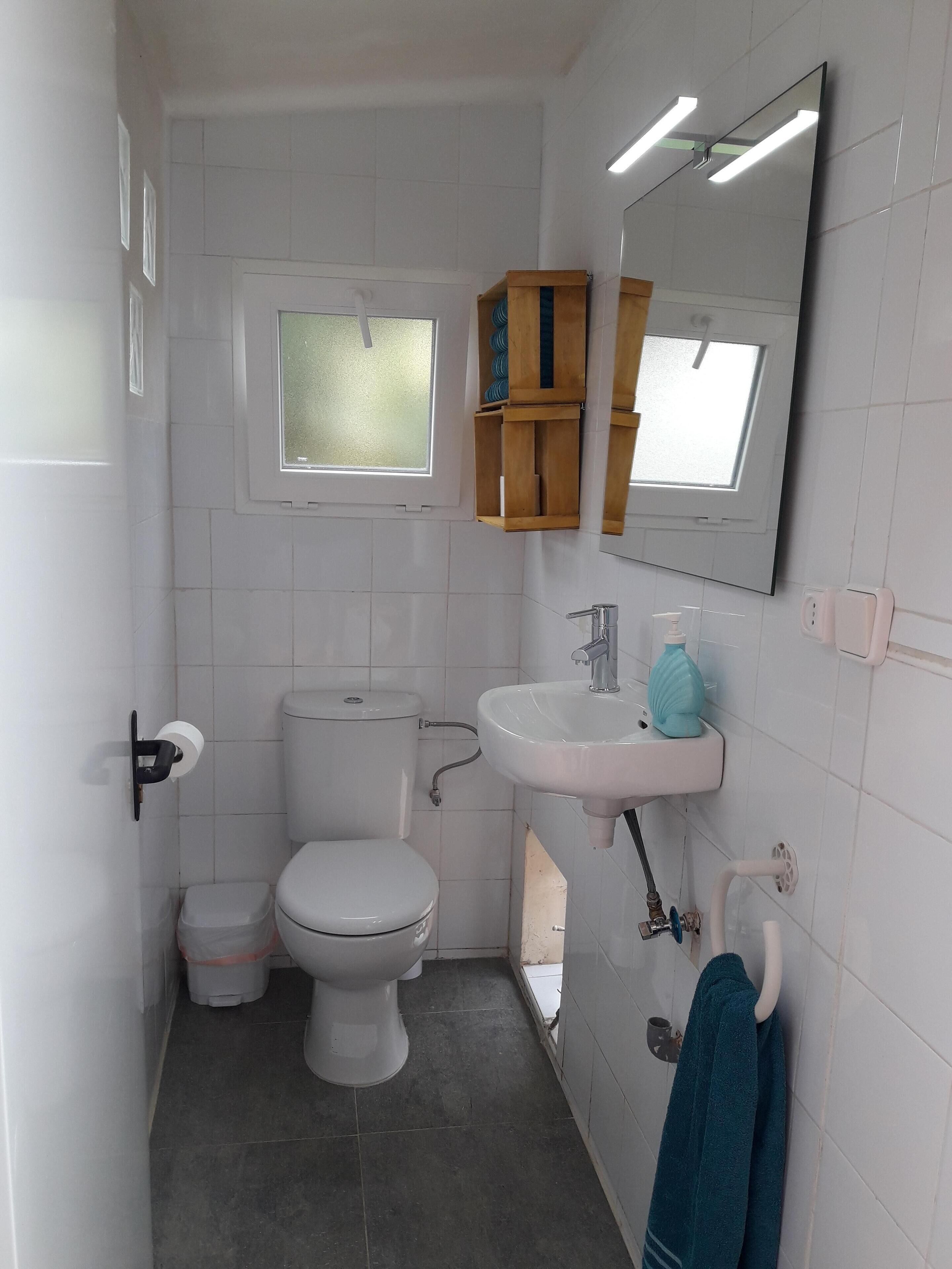 A compact bathroom with a toilet, sink, and a small window.