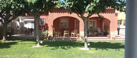 A red building with a patio area featuring outdoor furniture and potted plants.