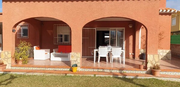 A building with two arched doorways, a patio with outdoor furniture, and potted plants. - House / Villa - Dénia (Dénia)
