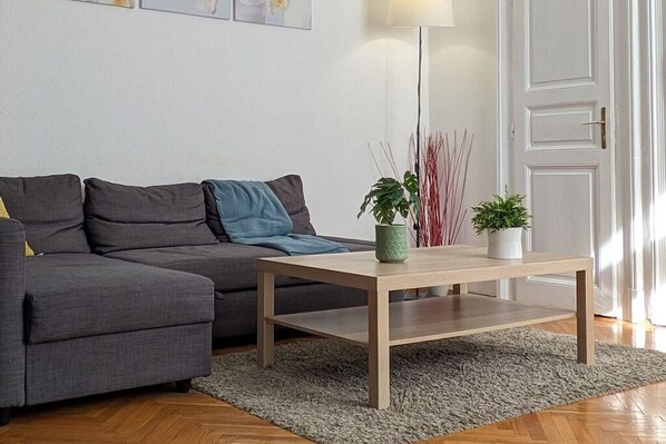 Un salon moderne avec un canapé gris, une table basse en bois et un tapis gris.
